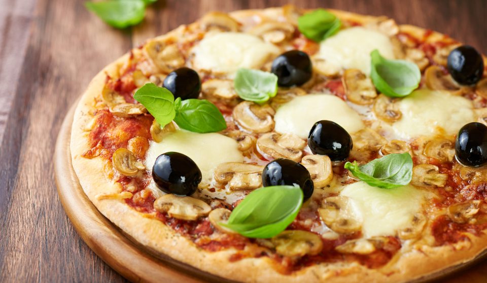 Pizza with mozzarella, mushrooms, black olives and fresh basil.